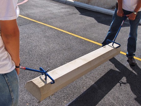 Two workers from SMR Striping in Houston TX installing a new Car Stop within a commercial parking lot.